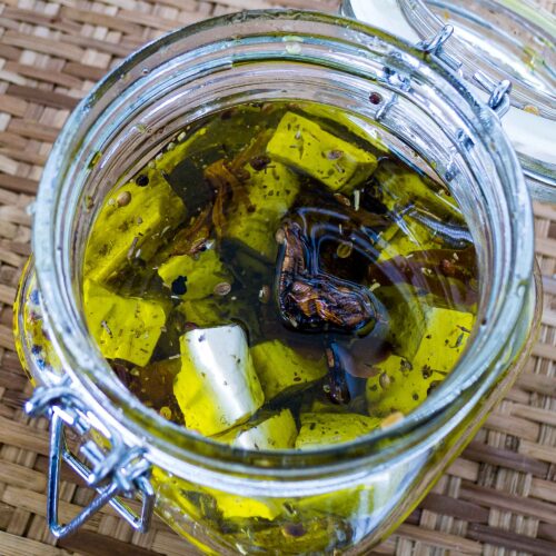 alt="a glass jar filled with preserved tofu packed in olive oil."