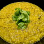 alt="Indian red lentil dahl topped with fresh coriander leaves."