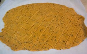 alt="the dough for the herbed lentil crackers has been cut into diamond shapes and are now ready to go into the oven."