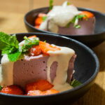 alt="vegan strawberry cheesecake with cashew nut drizzle, fresh mint and slices of strawberry."
