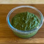 alt="a glass container with freshly made basil pesto."