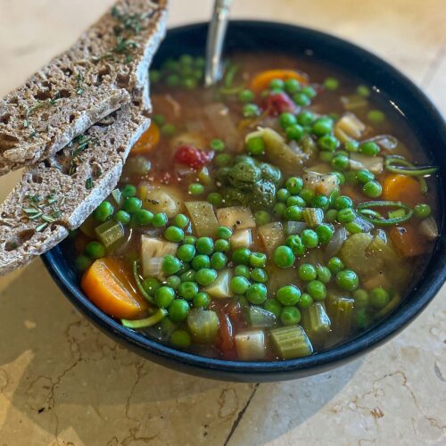 alt="chunky vegetable soup served with two slices of sourdough bread."
