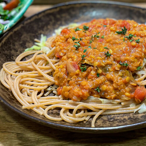 alt="red lentil Bolognese sauce over whole wheat spaghetti."