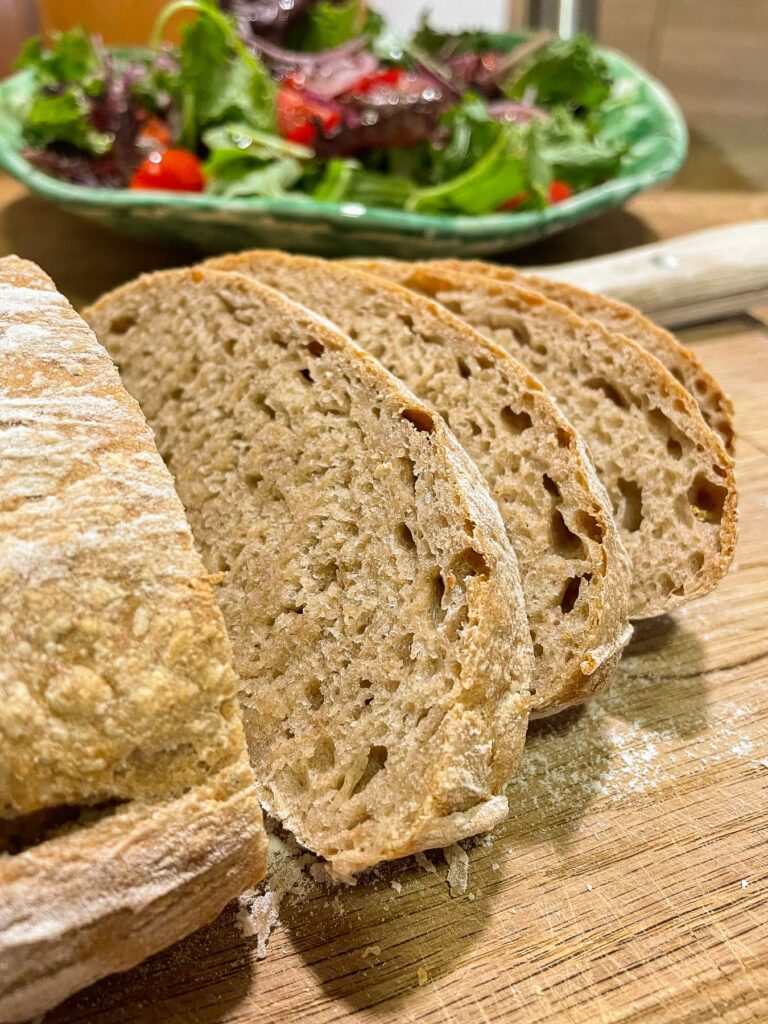 Slices of sourdough bread with a large mixed salad in the background.