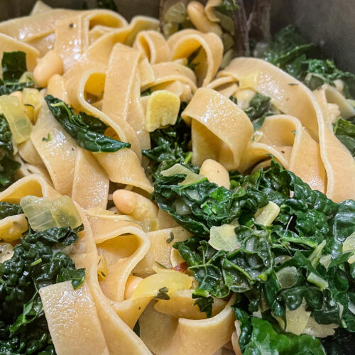 alt="a close up of some white beans and kale pasta."