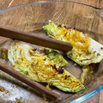 alt="a close up of some oven roasted heat cabbage wedges in an oven proof glass dish."