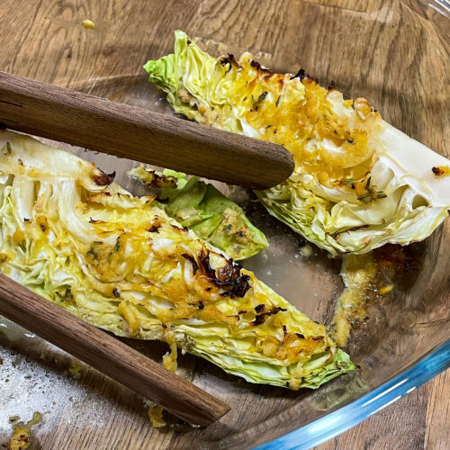alt="a close up of some oven roasted heat cabbage wedges in an oven proof glass dish."