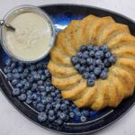 alt=a round pear cake served with the pear cream and blueberries."