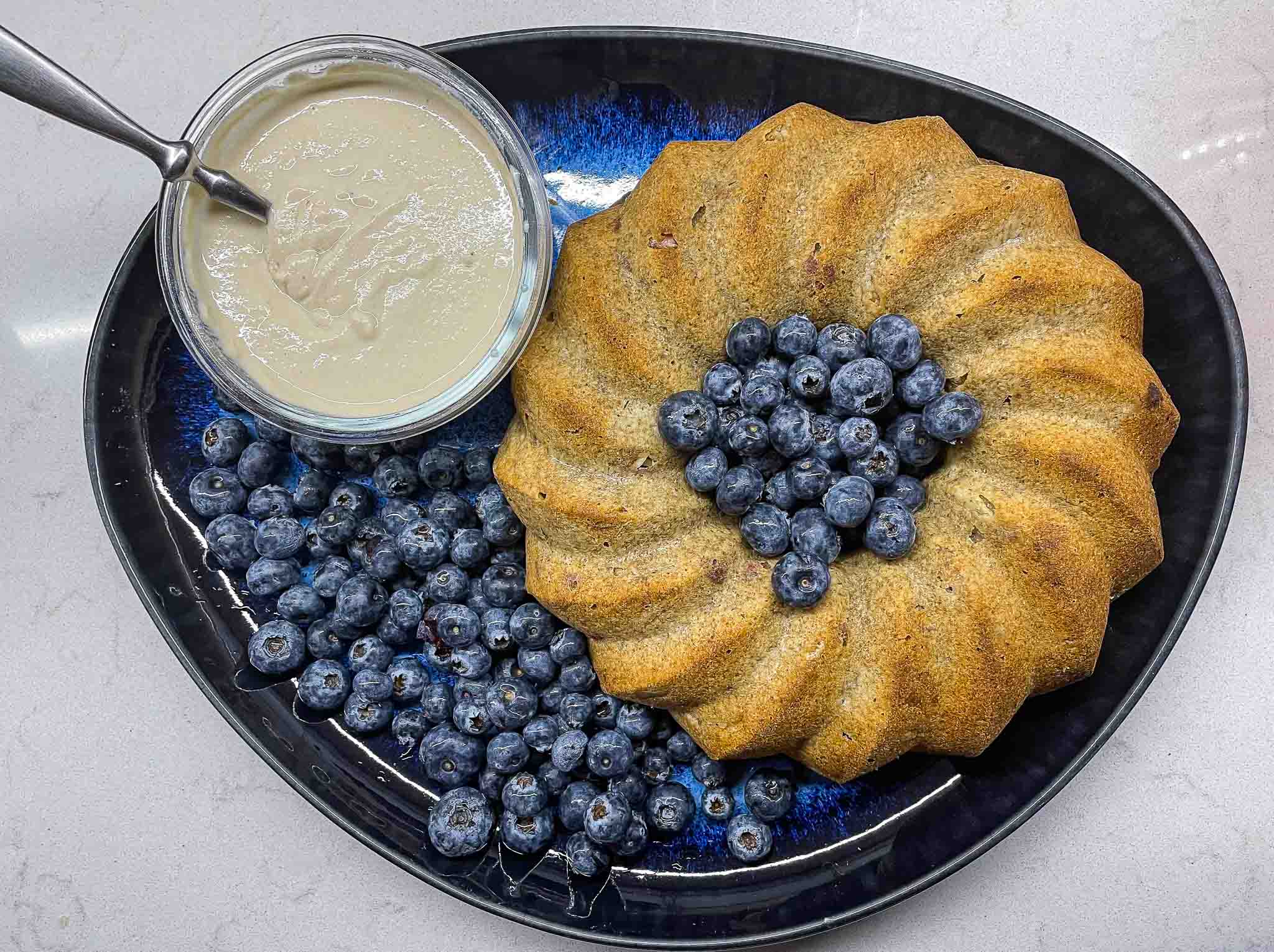alt="a round pear cake served with the pear cream and blueberries."