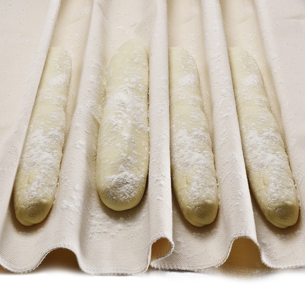 Four baguettes resting in a neatly folded cloth.