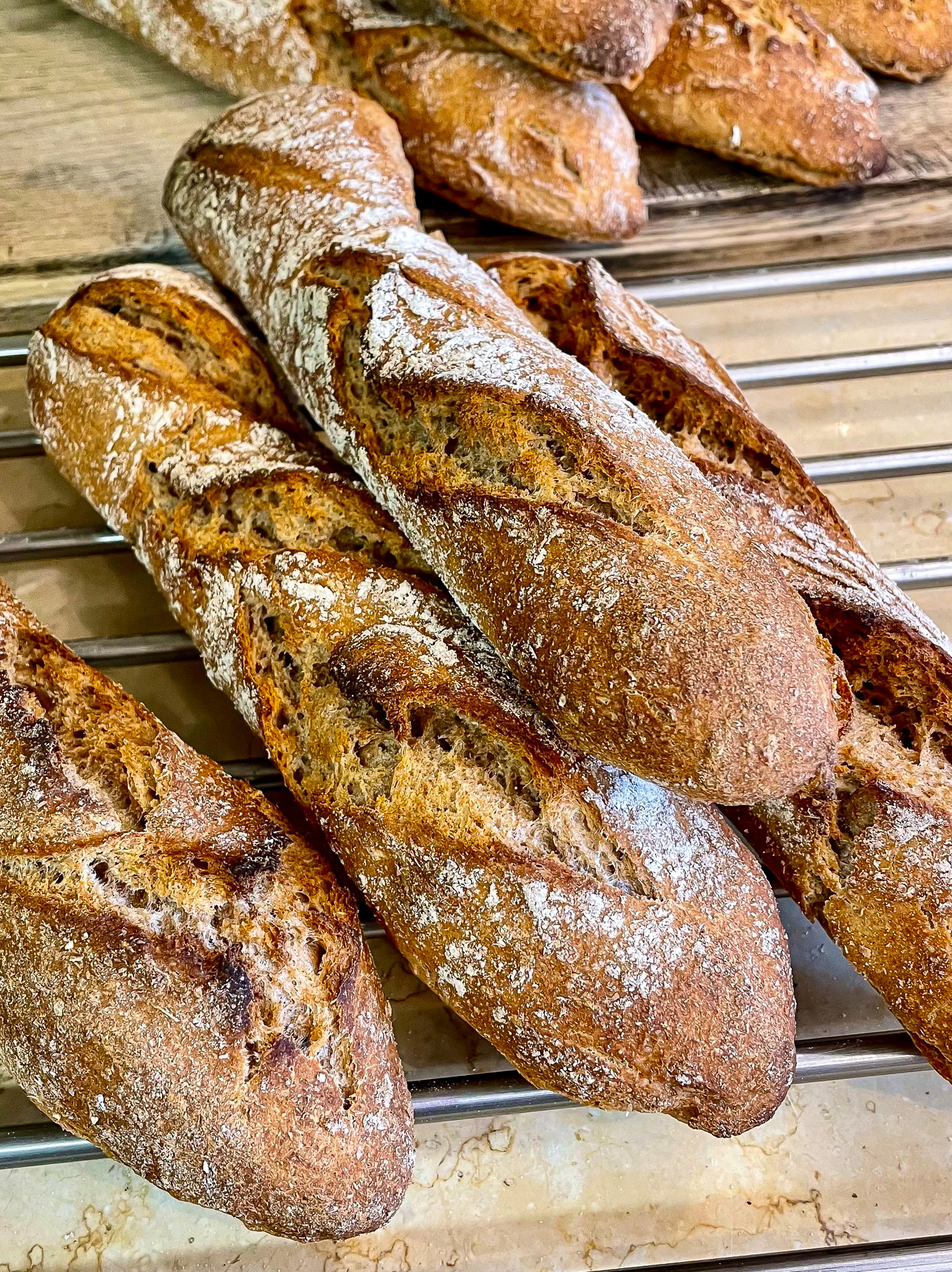 alt="a small pile of freshly made sourdough baguettes."