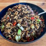 alt="a big bowl of wild rice, lentils and orzo with colorful red pepper, purple onions, and green celery."